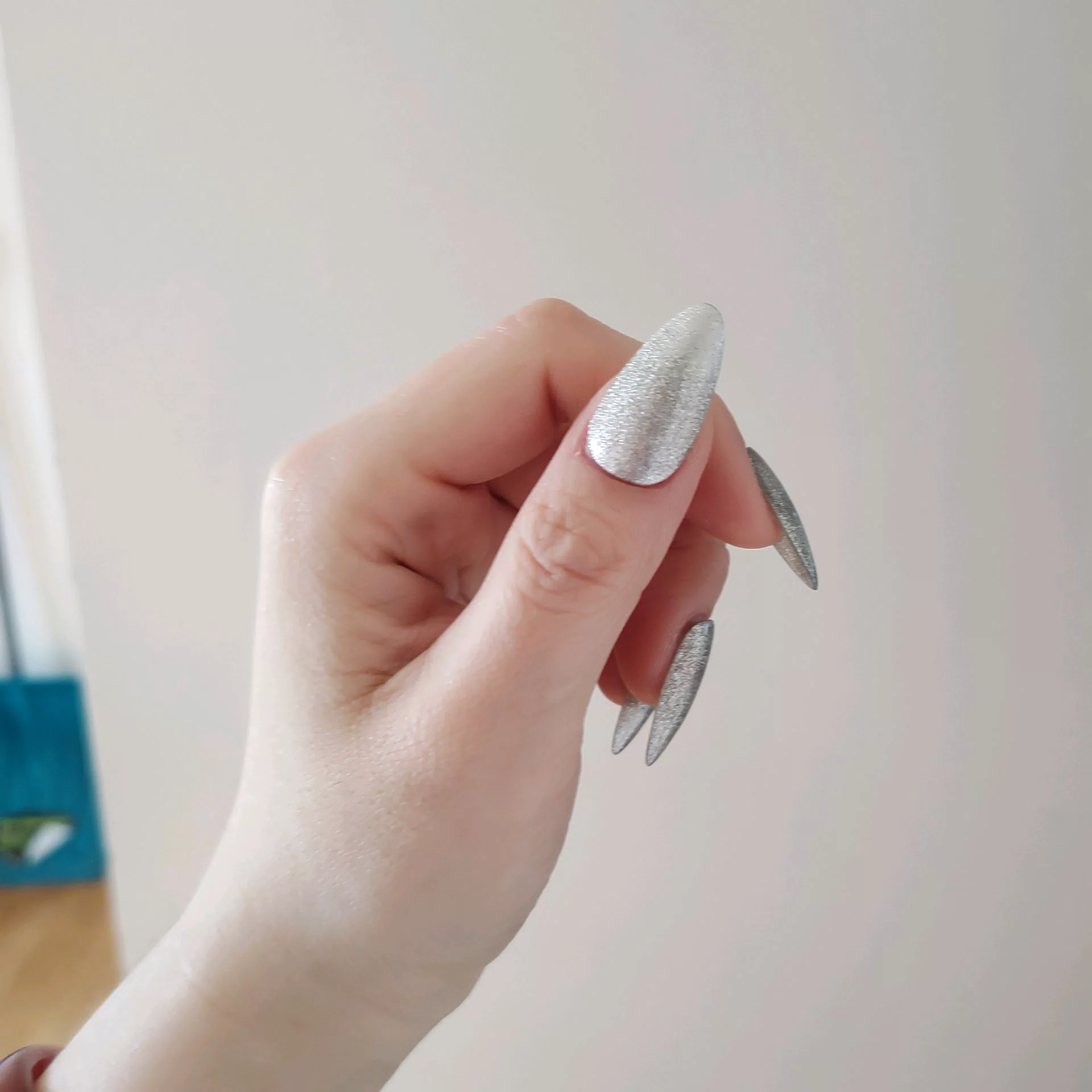 A close-up of a hand showcasing long, tapered stiletto-almond press-on nails featuring a luxurious, dimensional silver-charcoal velvet cat-eye magnetic shimmer that shifts dynamically in the light. — photo 2